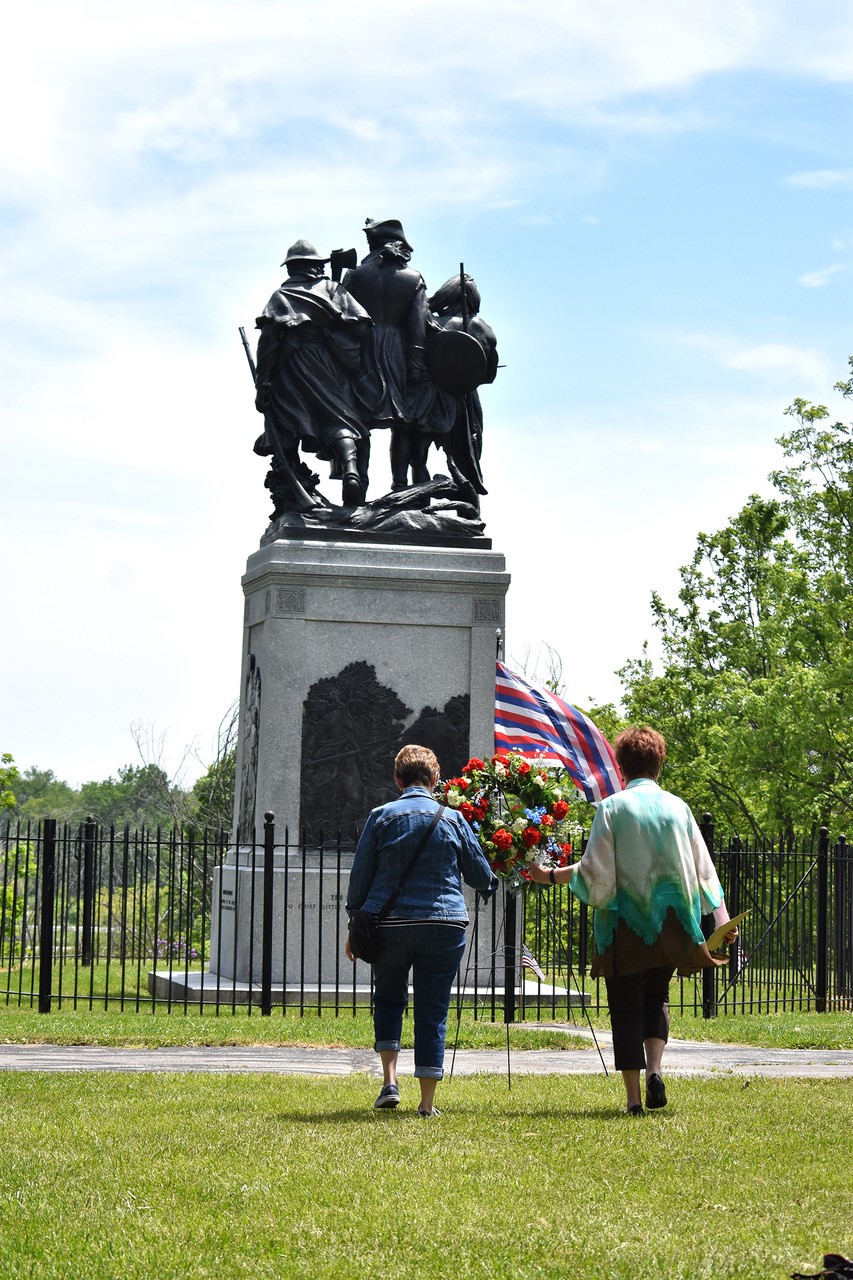 women laying wreath at monument